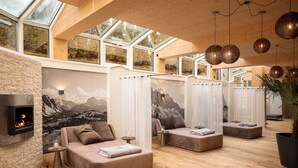 Et moderne spa-rum med pejs, store vinduer og et træloft.