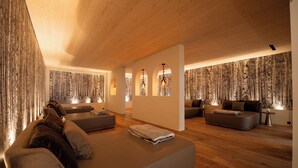 Et moderne interiør med træloft, sofa, lille bord og tapet med mønster.