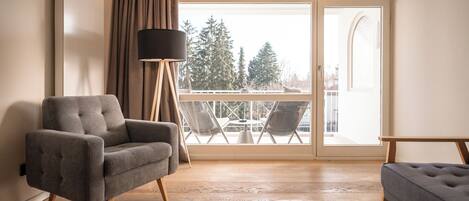 A modern living room with a grey sofa, a floor lamp, and a balcony with outdoor furniture.