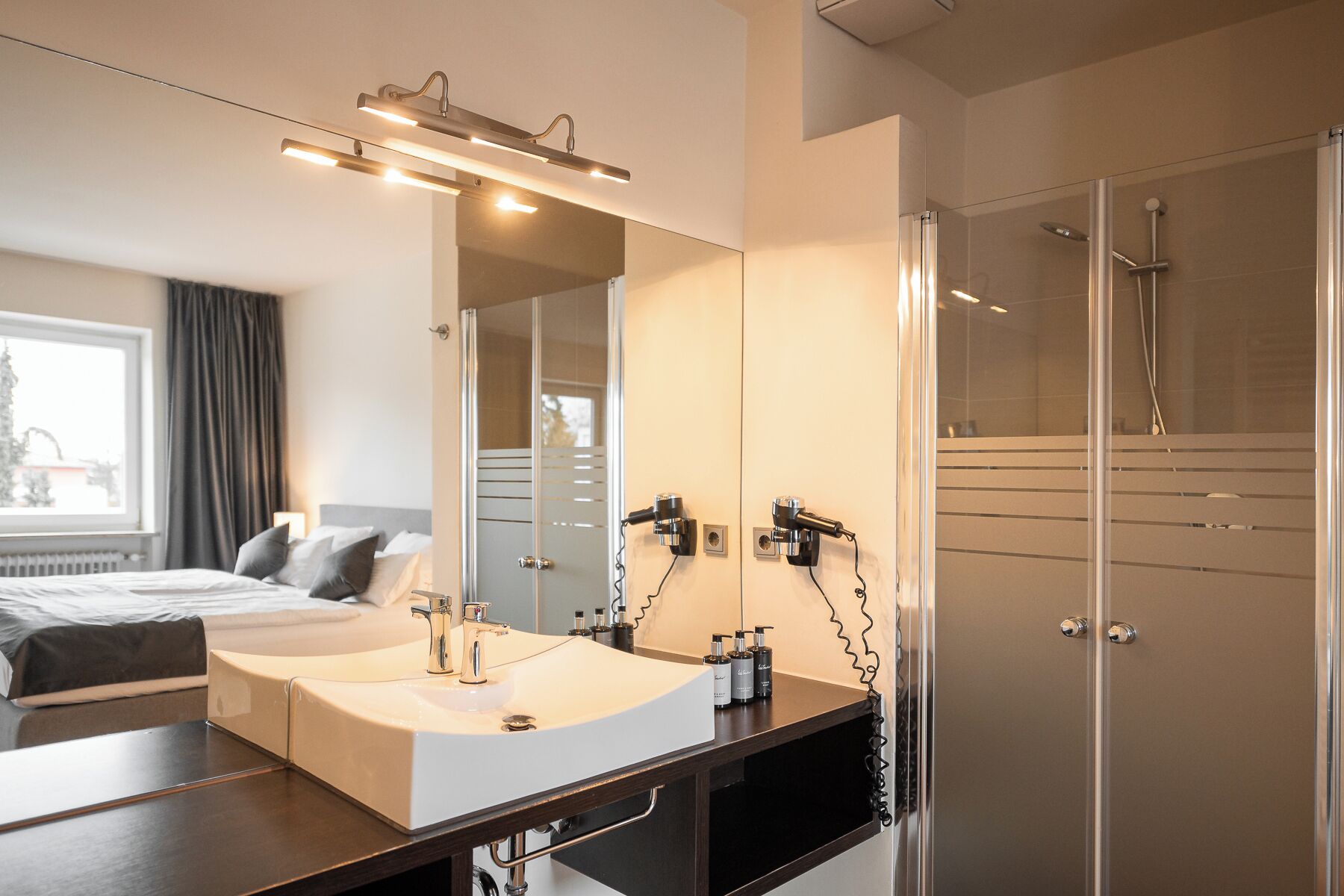 Un baño moderno con un espejo grande, un lavabo y una ducha.
