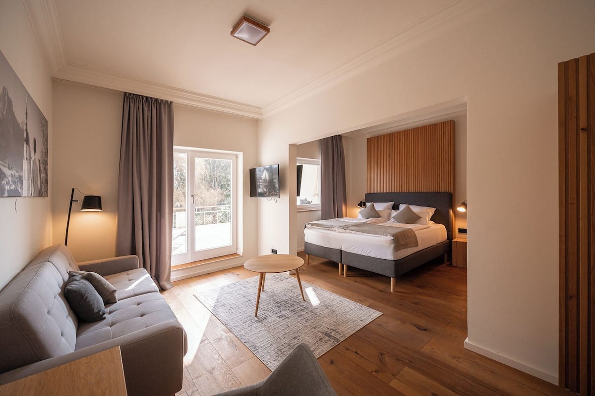 Un dormitorio moderno con una cama, un sofá, una mesita y un televisor.