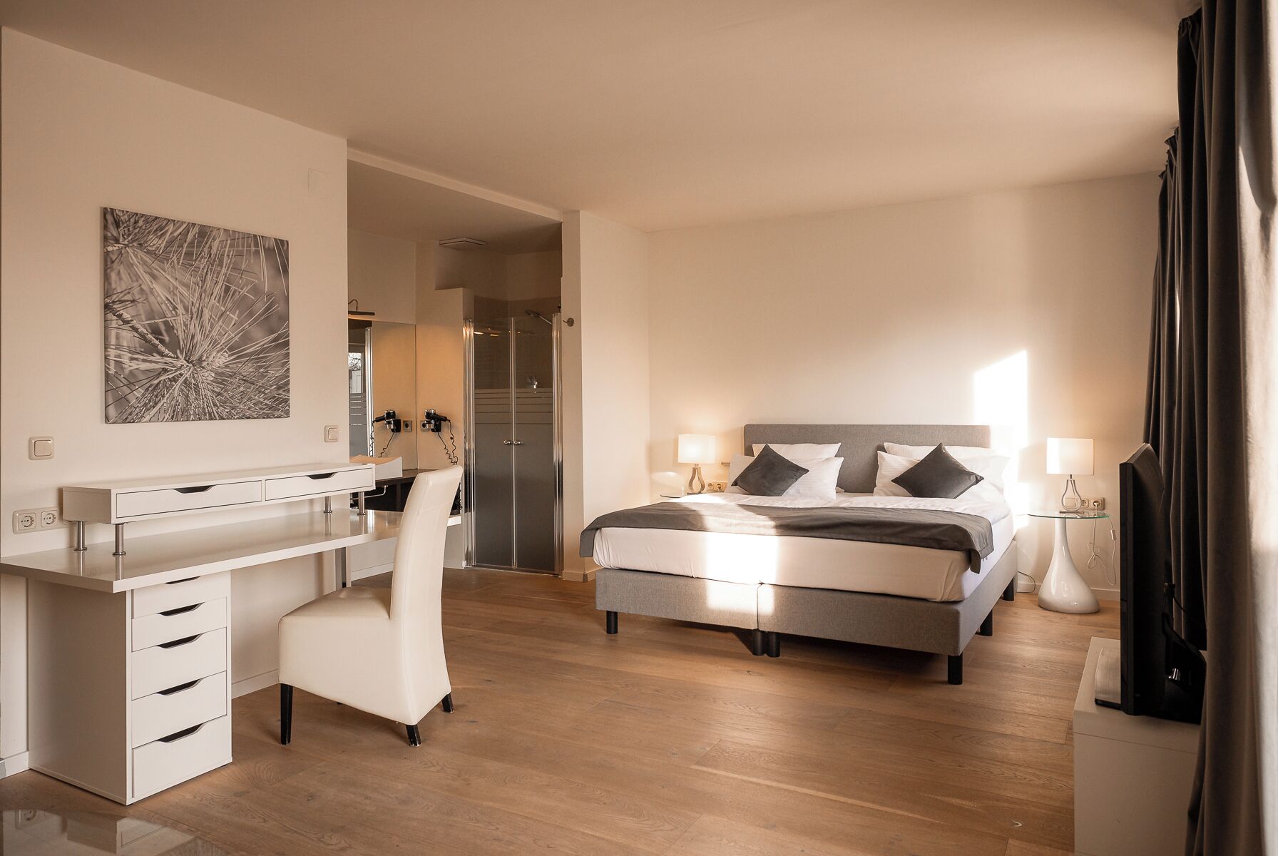 A modern hotel room with a bed, bedside tables, a desk, and a chair.