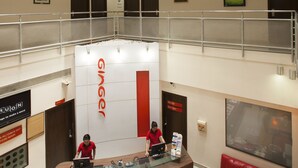 Un hall d’hôtel à plusieurs niveaux, avec un comptoir d’accueil, deux employés, un canapé rouge et une grande fenêtre.