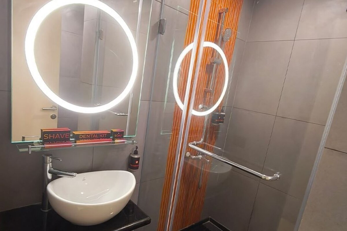 A modern bathroom with a round mirror, a sink, and a shower with a glass door.