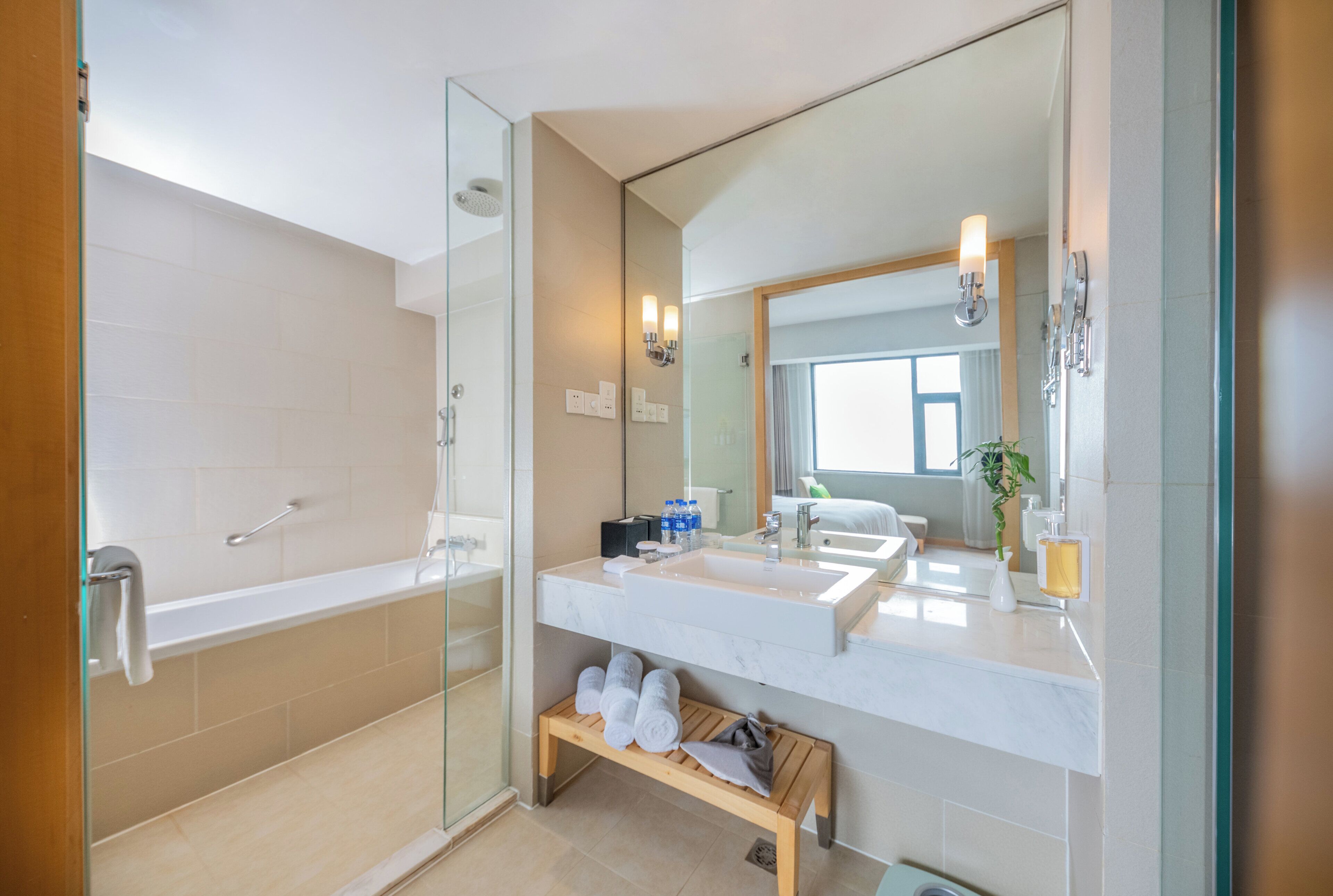 Un baño moderno con ducha de vidrio, un espejo grande y un tocador con lavamanos y encimera.