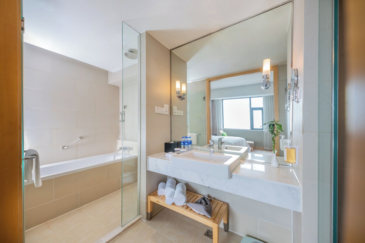 A modern bathroom with a glass-enclosed shower, a large mirror, and a vanity with a sink and countertop.