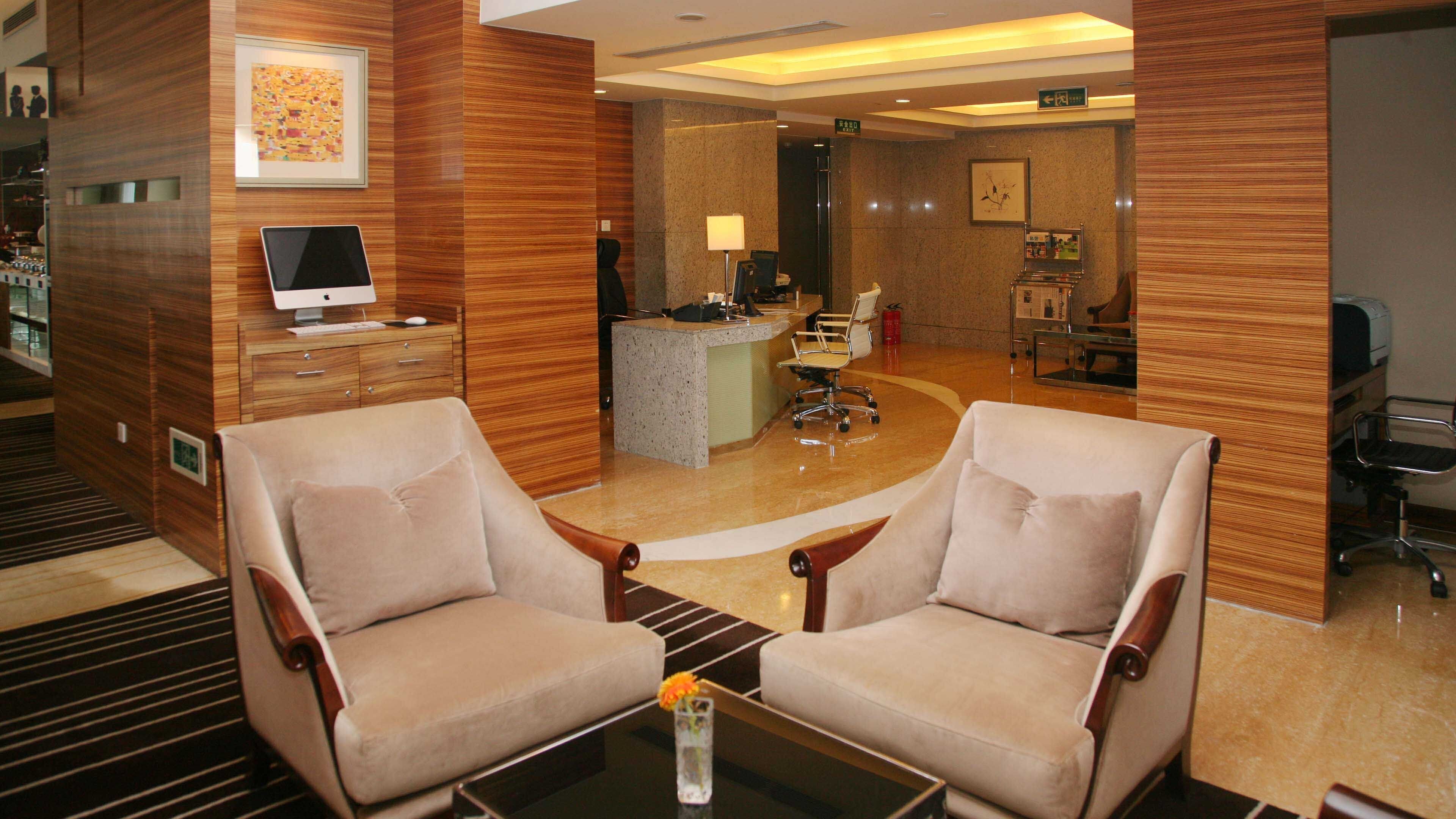 A hotel lobby with two armchairs, a reception desk, and a computer monitor.