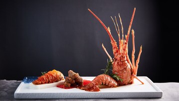 A lobster dish on a white rectangular plate with a dark background.