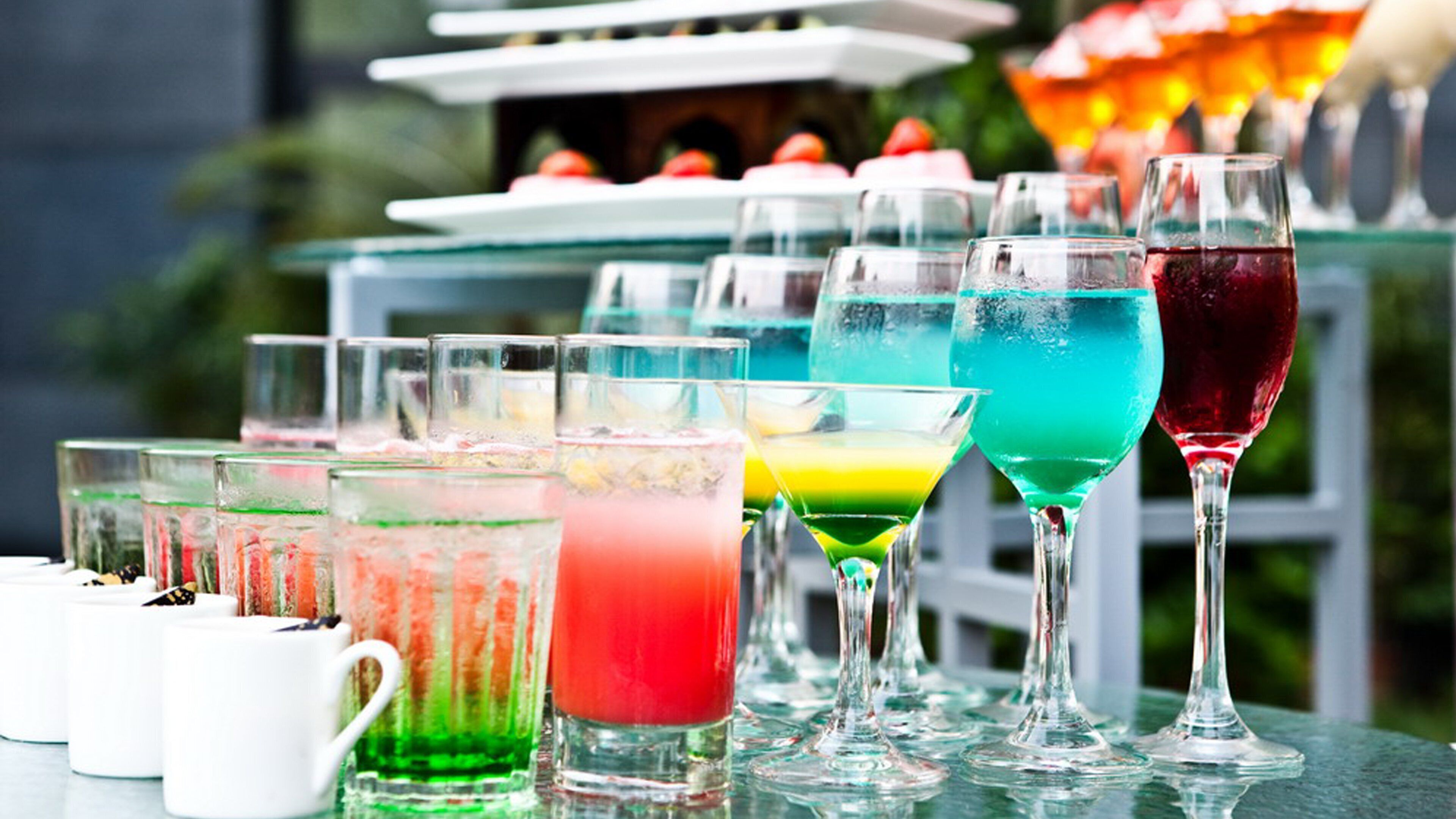 Une variété de boissons colorées servies dans des verres et des tasses, disposées sur une table.