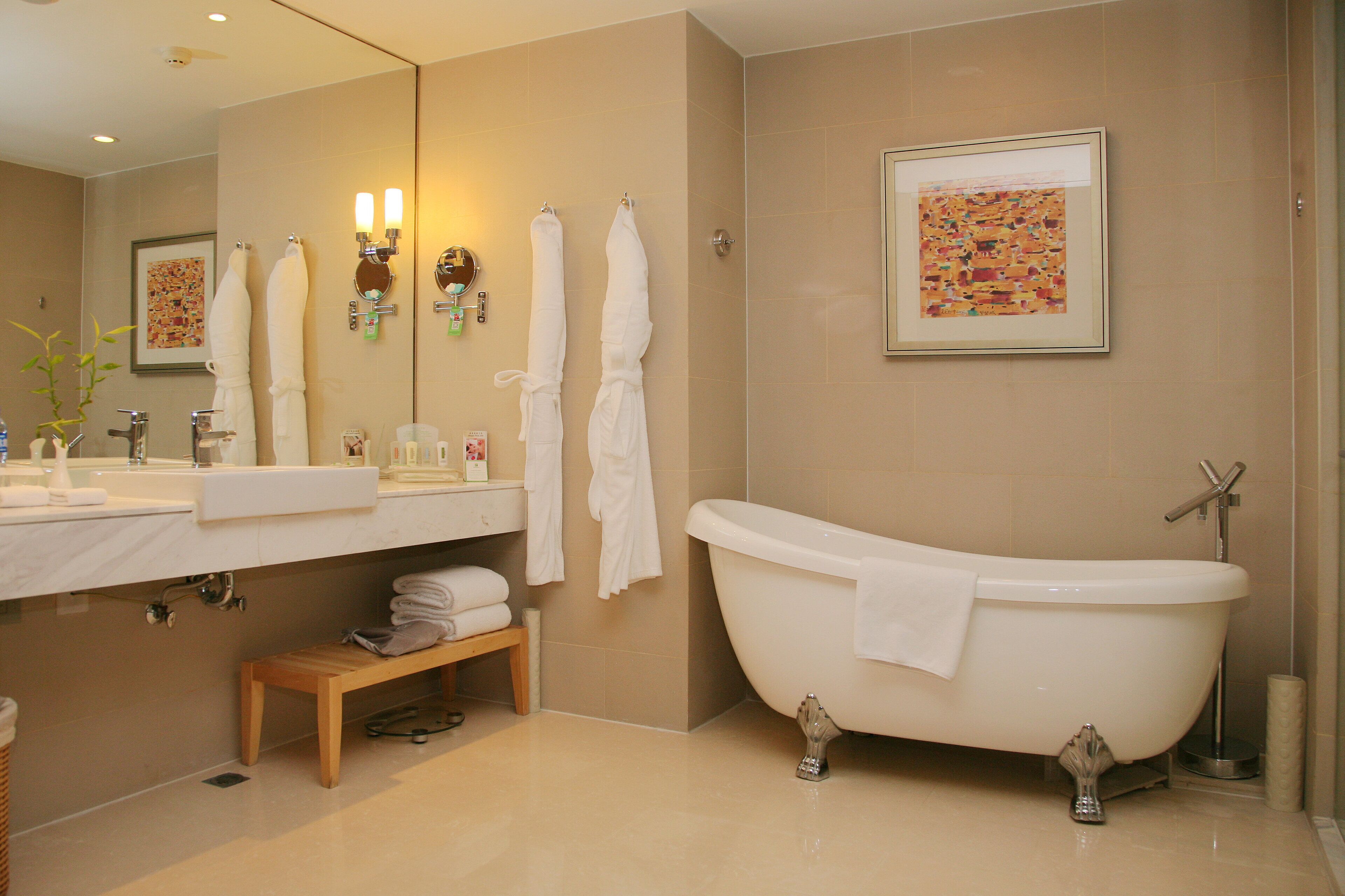 A bathroom with a bathtub, a sink, a mirror, and a bench.