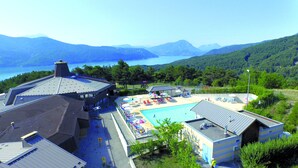Un hôtel doté d’une piscine, de chaises longues et offrant une vue sur les montagnes et le lac.
