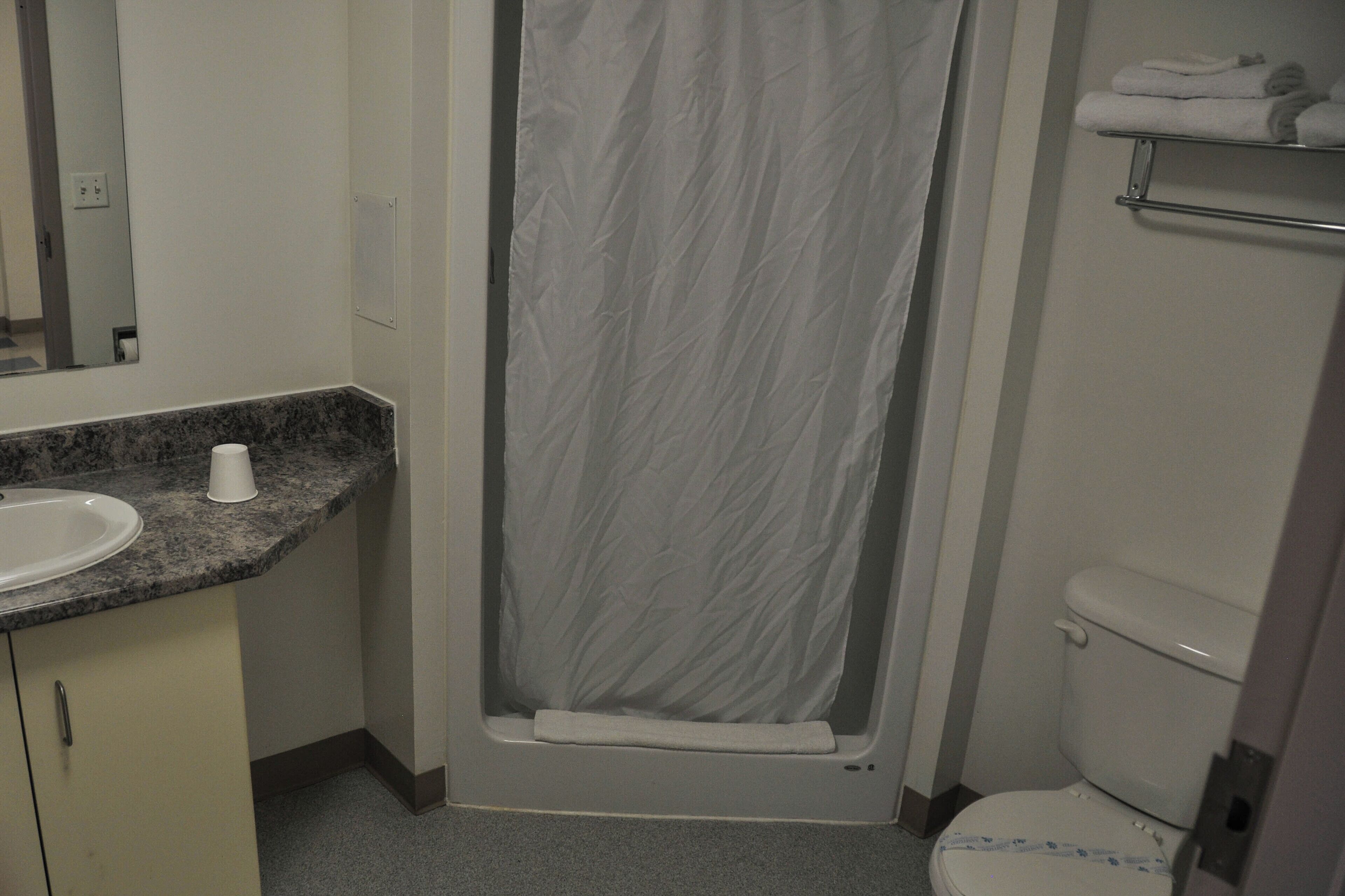 A bathroom with a shower curtain, a sink, a toilet, and a towel rack.