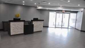 A reception area with two reception desks, a stone-textured counter, and a glass door leading outside. - Residence & Conference Centre - Kitchener Waterloo (Kitchener)