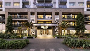 Un hotel de diverses plantes amb entrada central, balcons i plantes a l'exterior.