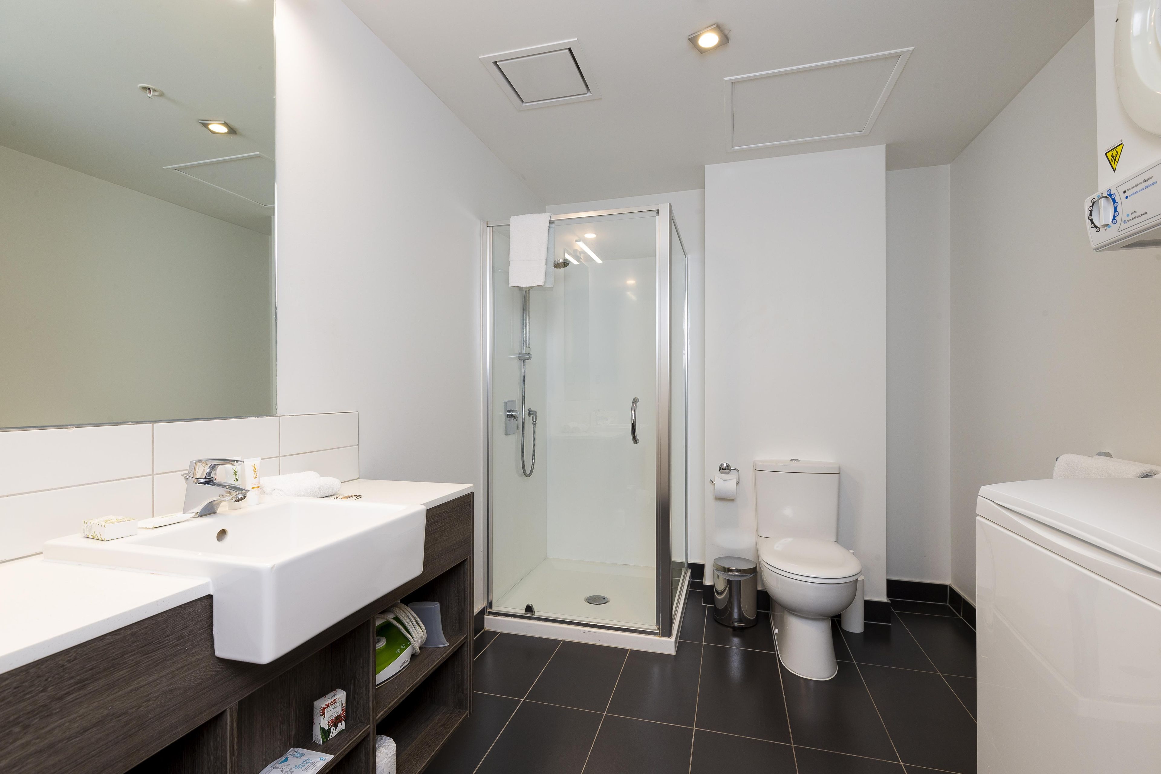 A modern bathroom with a glass-enclosed shower, a white sink, and a toilet.