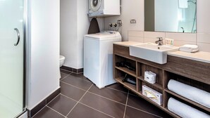 Un baño moderno con lavadora integrada, un espejo grande y un tocador con lavabo y perchero.