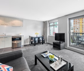 A modern apartment with a kitchen, dining area, living room, and a balcony with a city view.