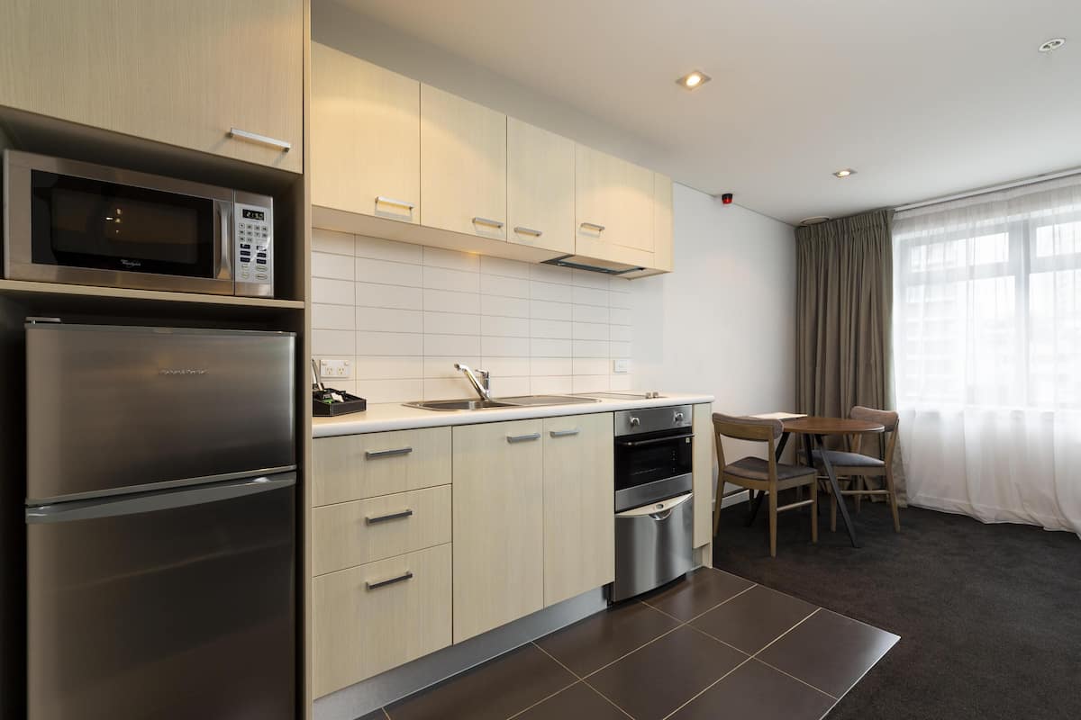 A modern kitchen with a microwave, refrigerator, oven, and sink. There is a dining area with a table and chairs.