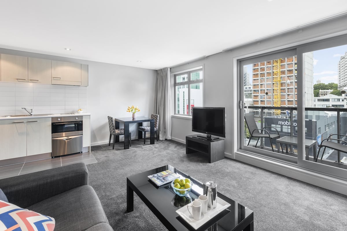 A modern living room with a sofa, coffee table, TV, and dining area.