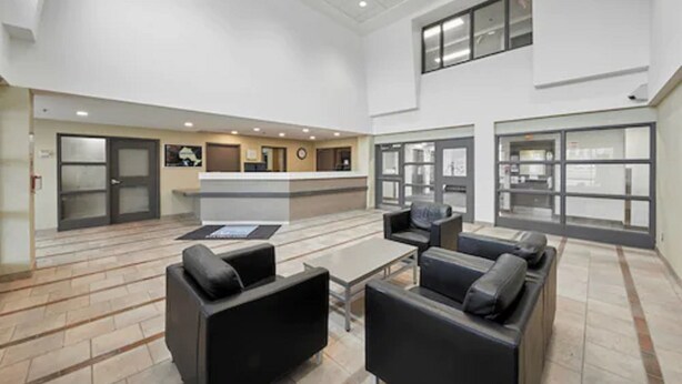 A spacious lobby with a reception desk, seating area with sofas, and large windows. - Residence and Conference Centre – King City (King)