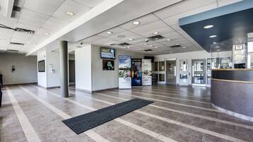 A spacious lobby with a reception desk, informational posters, and a tiled floor.
