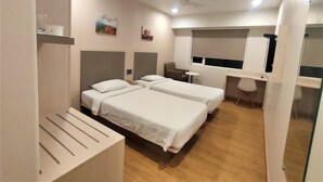 A hotel room with two beds, a desk, a chair, a small table, and a window. - Ginger Pune Pimpri (Pune)