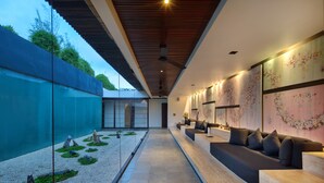 Un interior moderno con un largo pasillo, zona de estar con cojines y decoración mural.