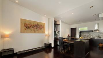 A modern kitchen with dark wood flooring, a central island, and recessed lighting.
