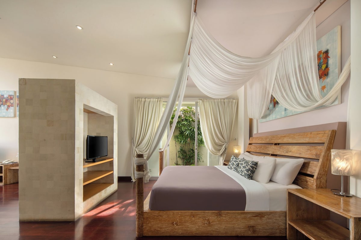 A modern bedroom with a wooden bed, a television, and a large window with curtains.