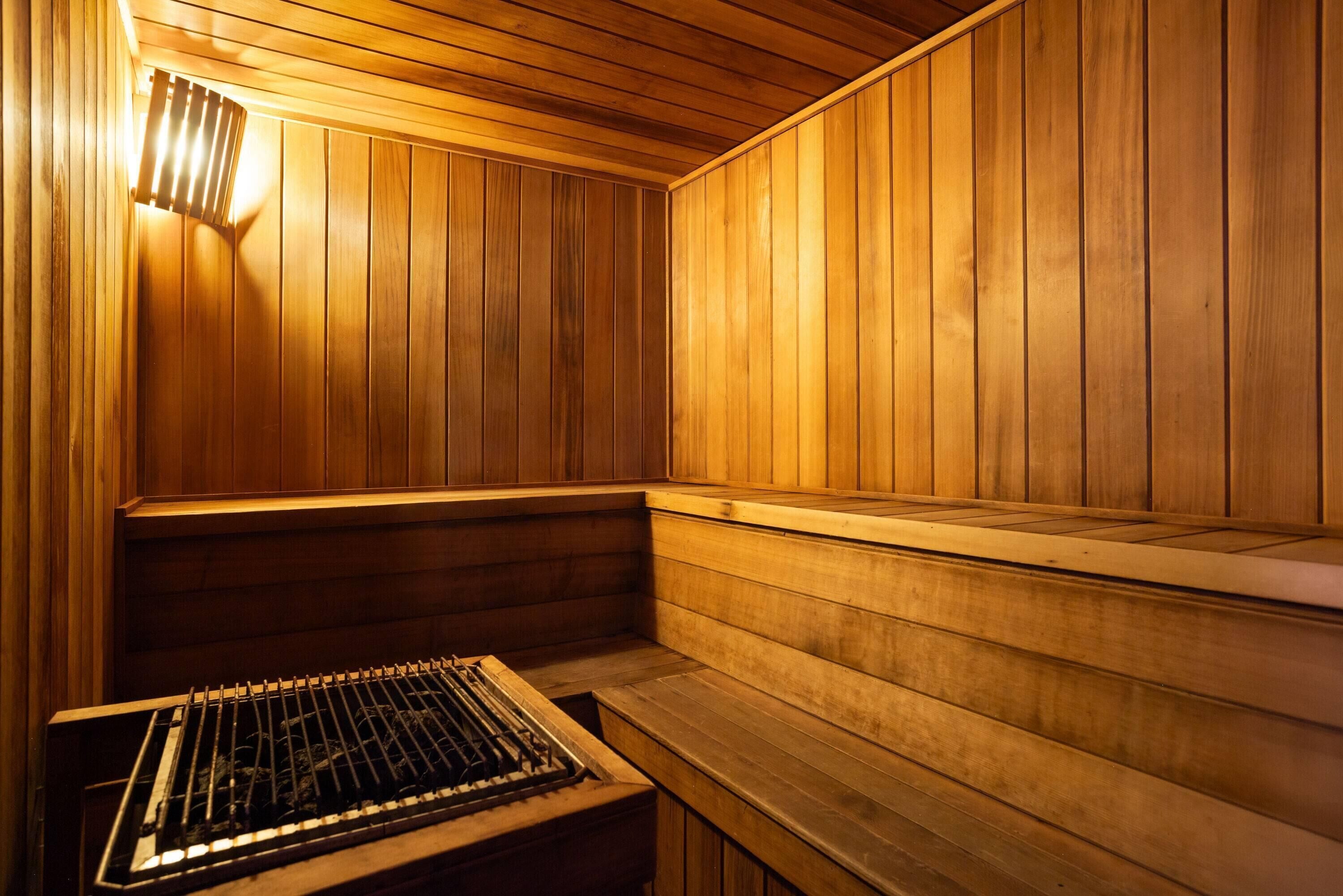Una sauna con paredes y bancos de madera, un banco en primer plano y un calentador en la parte frontal.