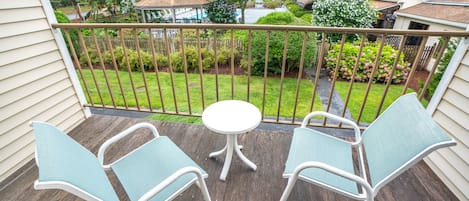 A wooden deck with two light blue chairs and a small white table.