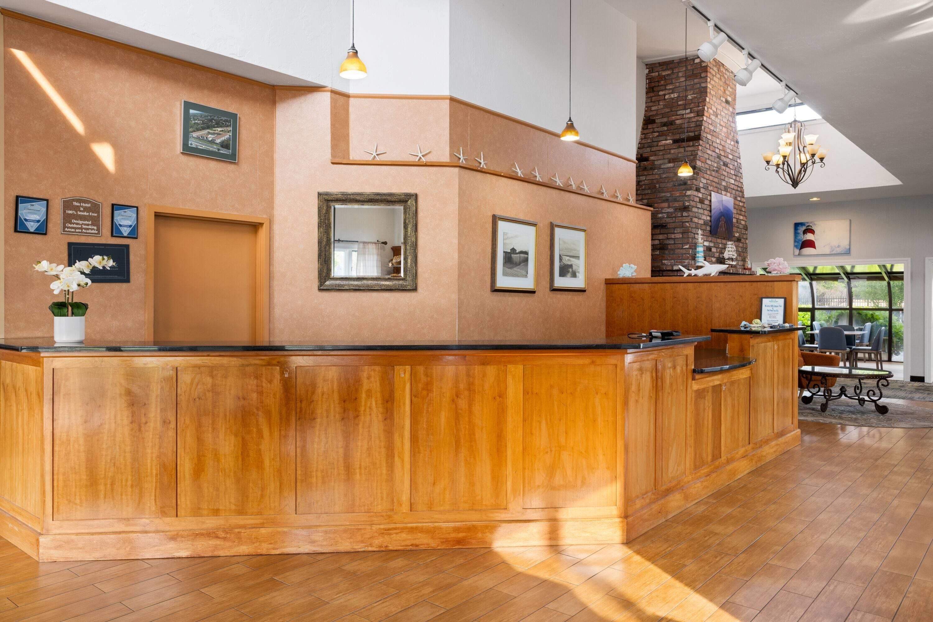 A reception area with a wooden reception desk, framed pictures on the wall, and a brick fireplace.