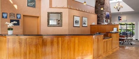 Un área de recepción con un mostrador de madera, cuadros enmarcados en la pared y una chimenea de ladrillo.