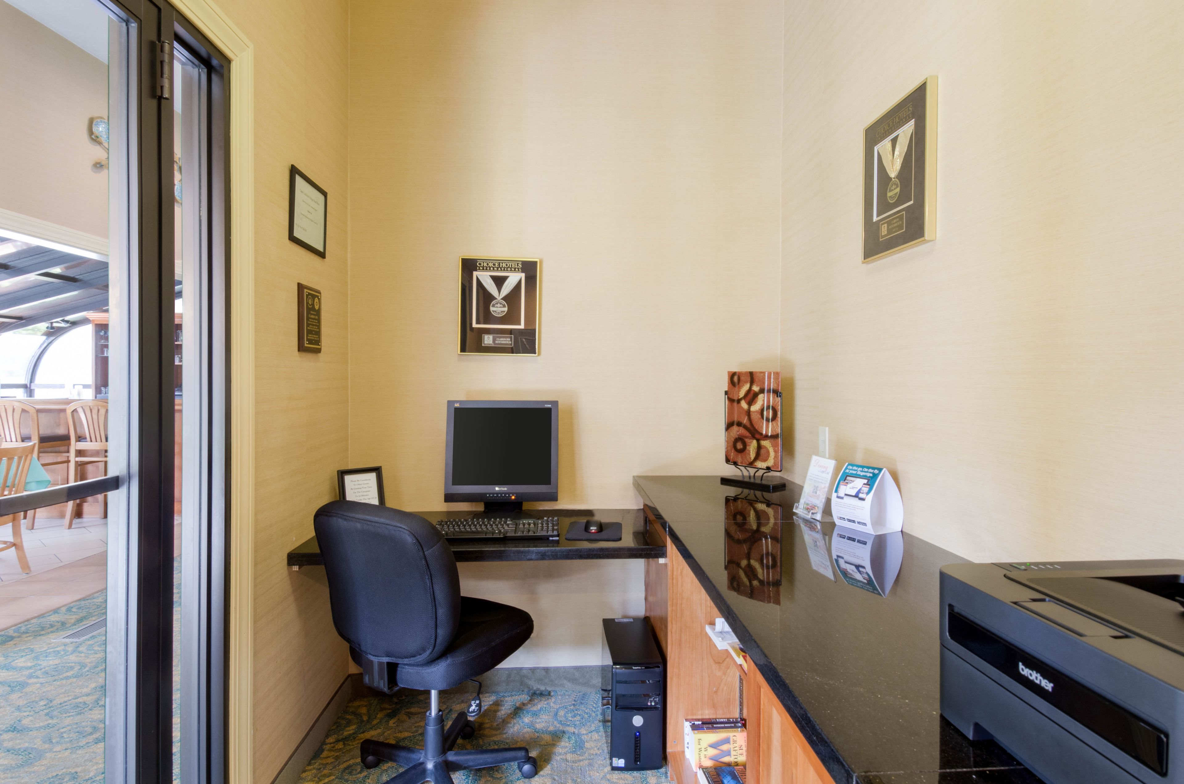 A hotel reception area with a desk, computer, chair, and a printer.