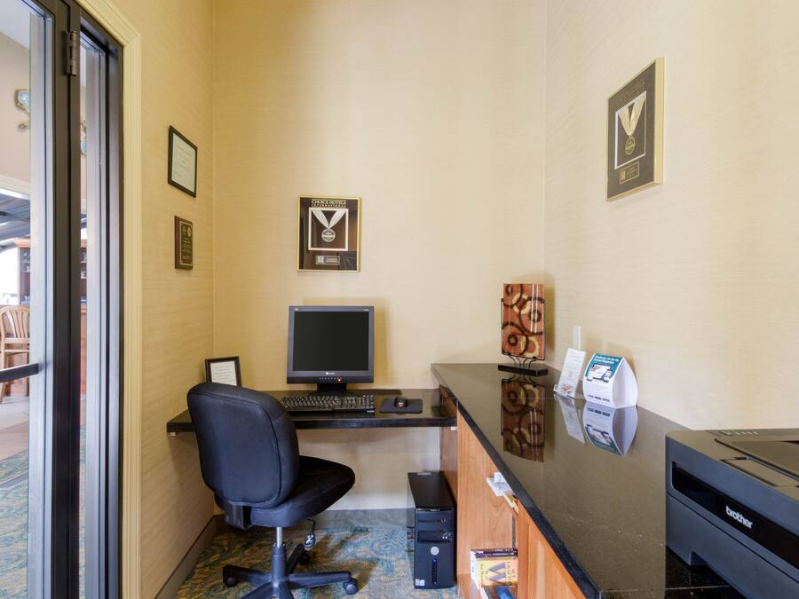 A hotel reception area with a desk, computer, chair, and a printer.