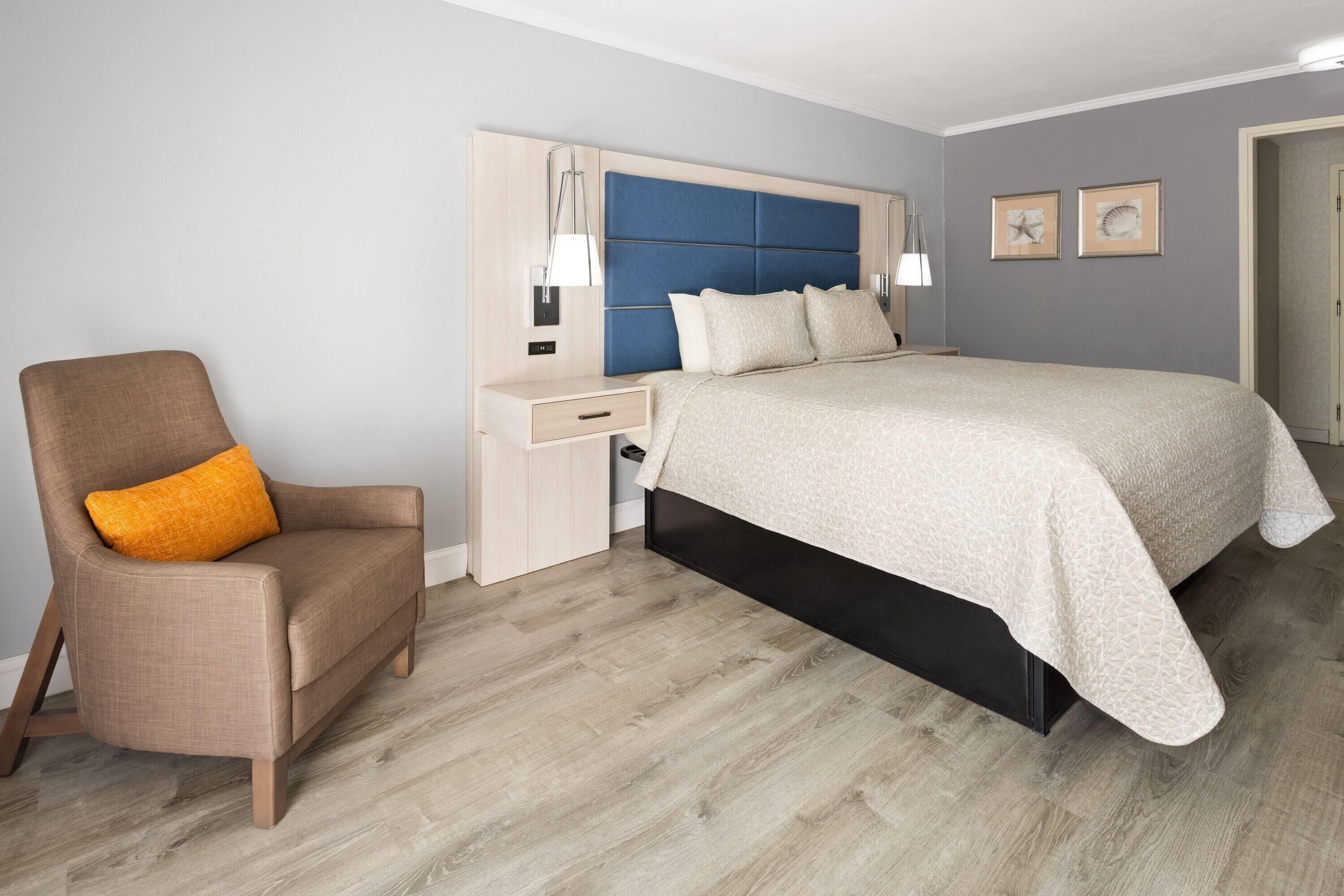 Une chambre à coucher comprenant un lit, une table de chevet, une chaise et une lampe fixée au mur.
