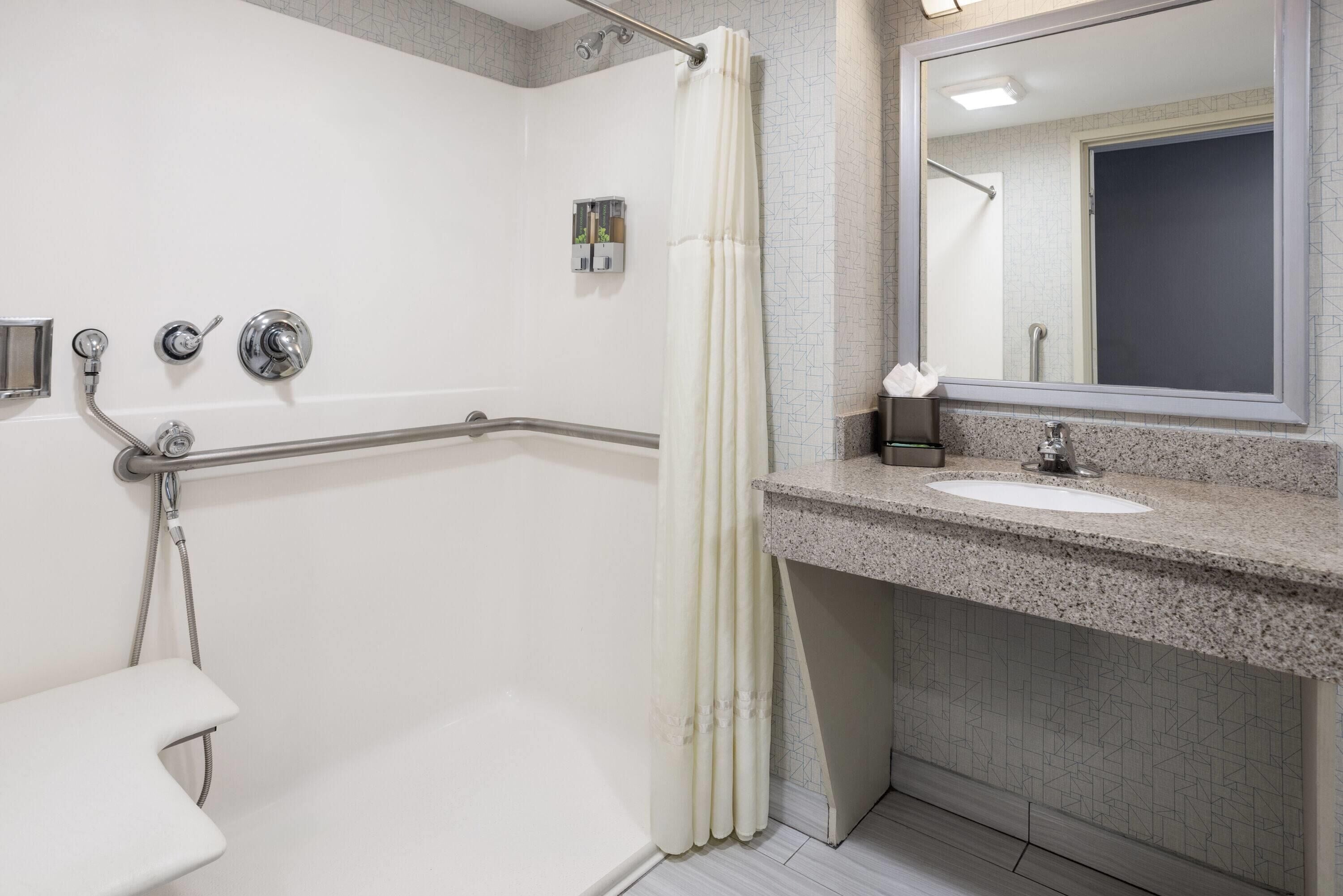 Un baño moderno con cabina de ducha, tocador con lavamanos y un espejo grande.