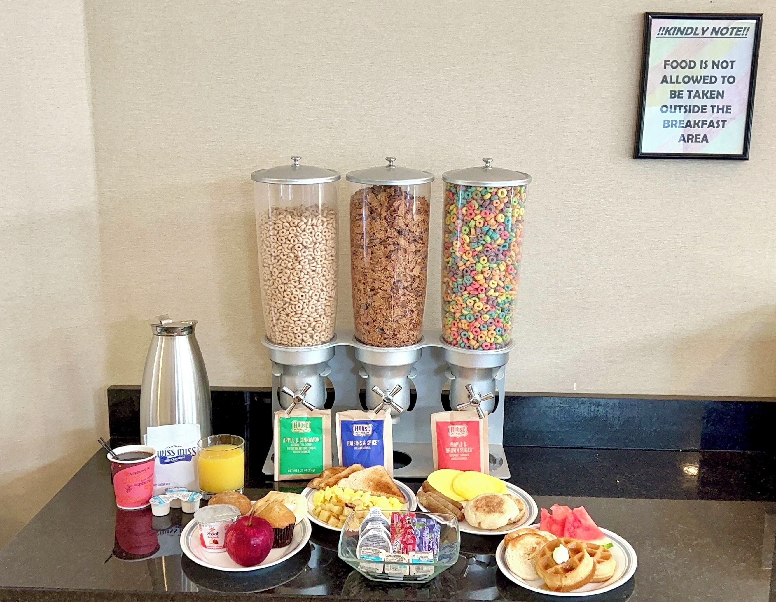 Un bufé de desayuno con cereales, granola y barritas de cereales, además de diversas opciones para el desayuno y bebidas.