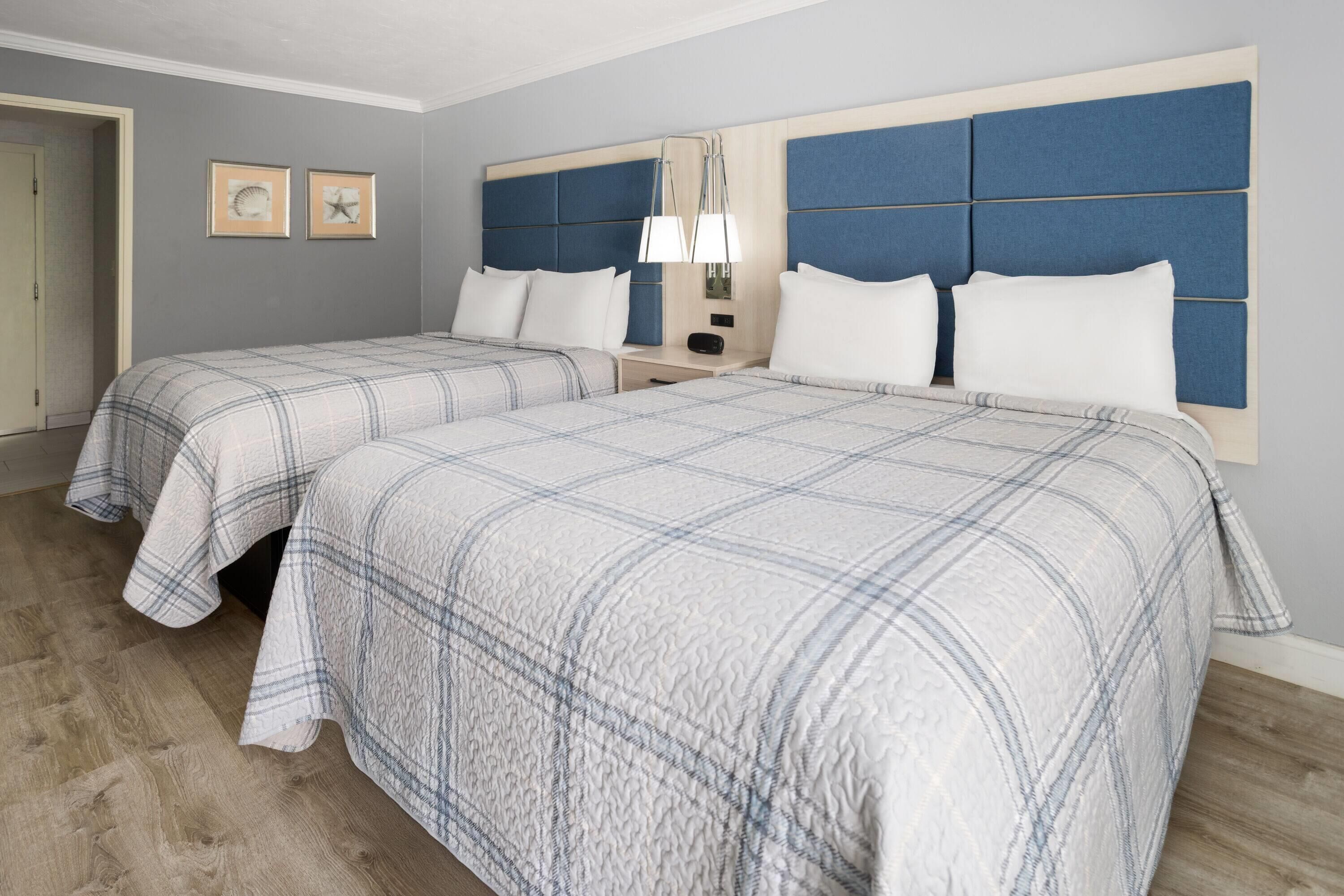 Une chambre d’hôtel avec deux lits, une table de chevet et une lampe fixée au mur.