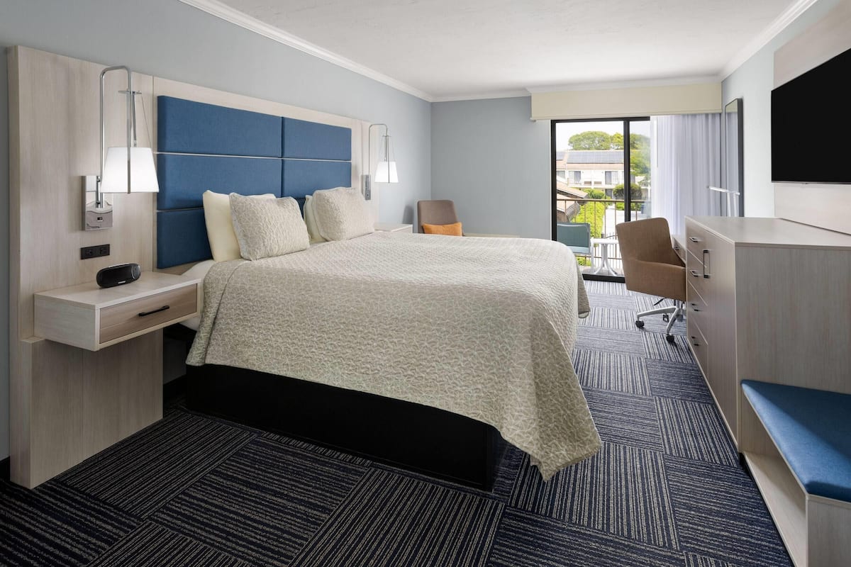 Une chambre d’hôtel moderne équipée d’un grand lit, d’un bureau, d’une chaise et d’un téléviseur.