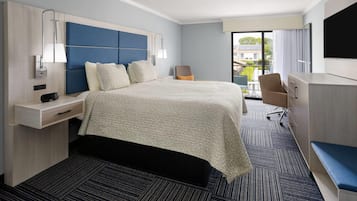Una habitación de hotel moderna con una cama grande, un escritorio, una silla y un televisor.