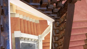A wooden staircase with a red carpeted landing area and a small red box on the floor.