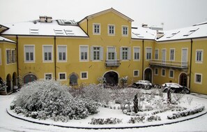 A yellow building with multiple windows and a snow-covered garden. - Grand Hotel Entourage Palazzo Strassoldo (Gorizia)