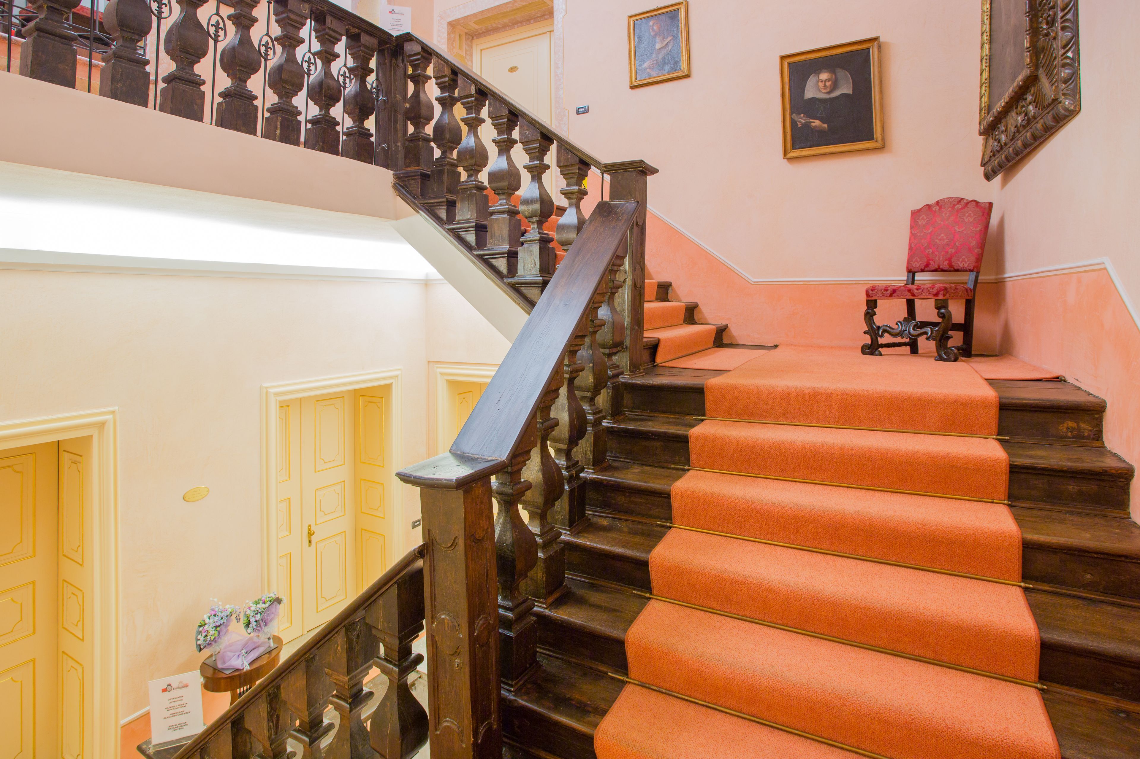 A grand staircase with ornate balusters and a red carpeted landing.