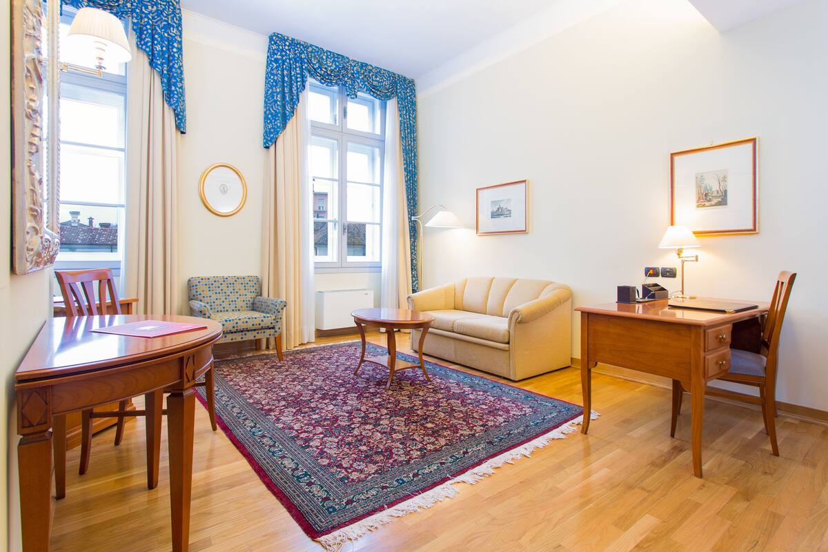 A living room with a wooden dining table, a sofa, a coffee table, and a rug.