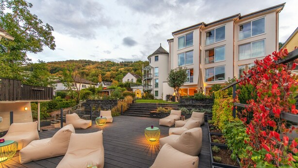 A rooftop patio with outdoor seating and a view of a hillside.