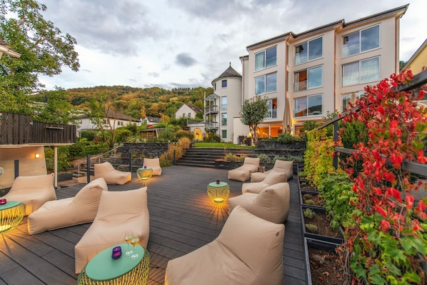 A rooftop patio with outdoor seating and a view of a hillside.
