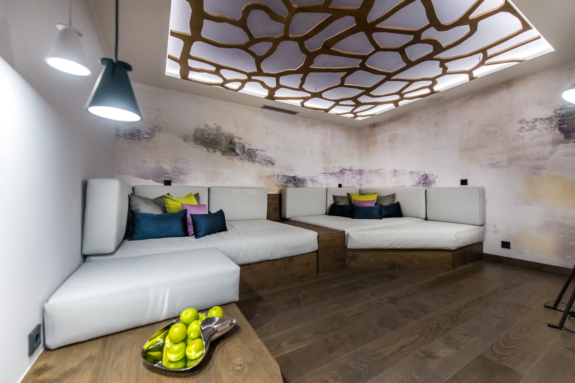 Un moderno spa con dos sofás blancos, suelo de madera y techo con diseño geométrico.