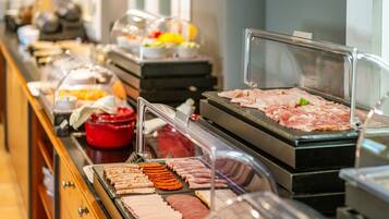 Un buffet proposant différentes sortes de viandes et un récipient rouge.