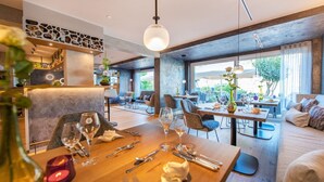 A restaurant with a wooden dining table, chairs, and a large window.